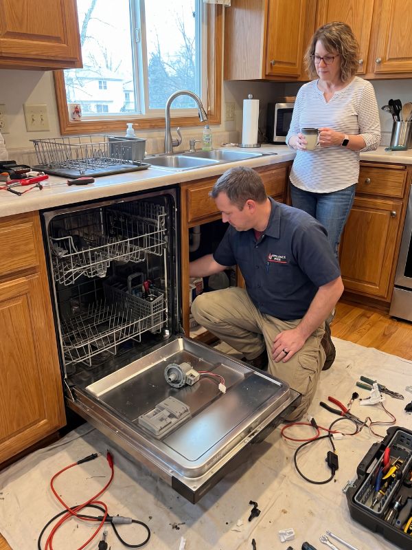 Appliance repair technician servicing a built-in dishwasher — drainage, leak, and spray-arm diagnostics in a Round Rock, TX kitchen